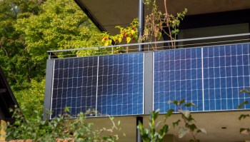 A balcony with solar panels and plants in the background.