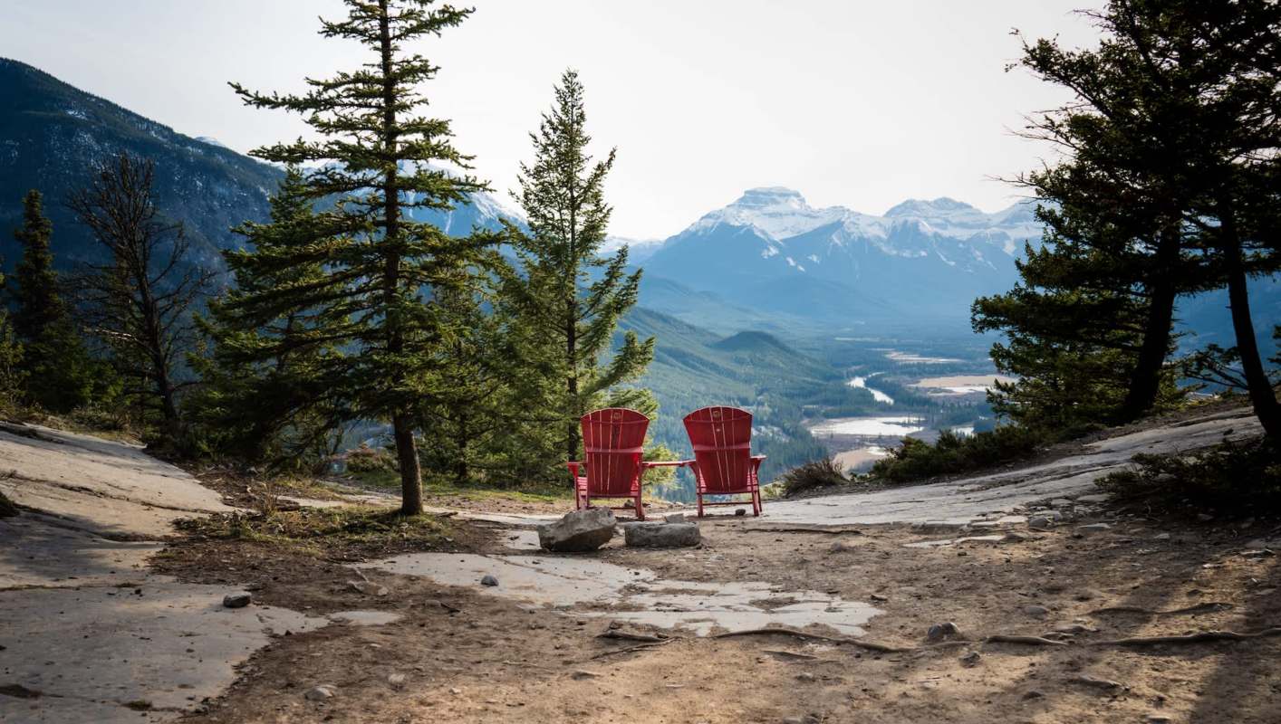 Red chairs overlooking a mountain trail.
