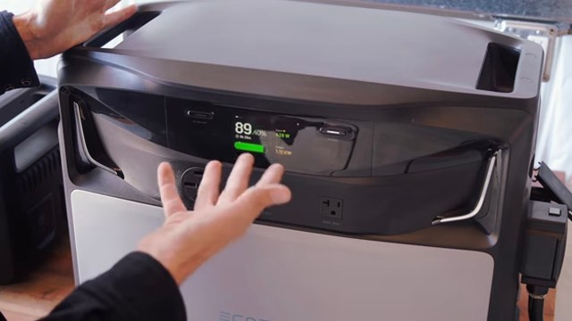 A hand interacts with the control panel of a power station displaying battery percentage and power usage.