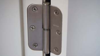 A metal door hinge attached to a white door.
