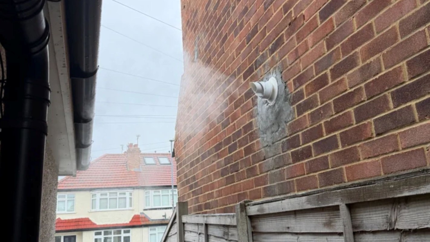A boiler flue mounted on a brick wall.