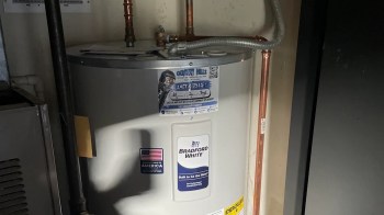A water heater with copper piping and a service sticker on the side.