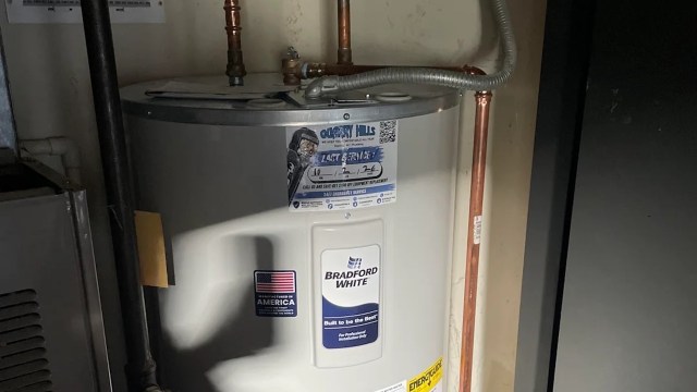 A water heater with copper piping and a service sticker on the side.