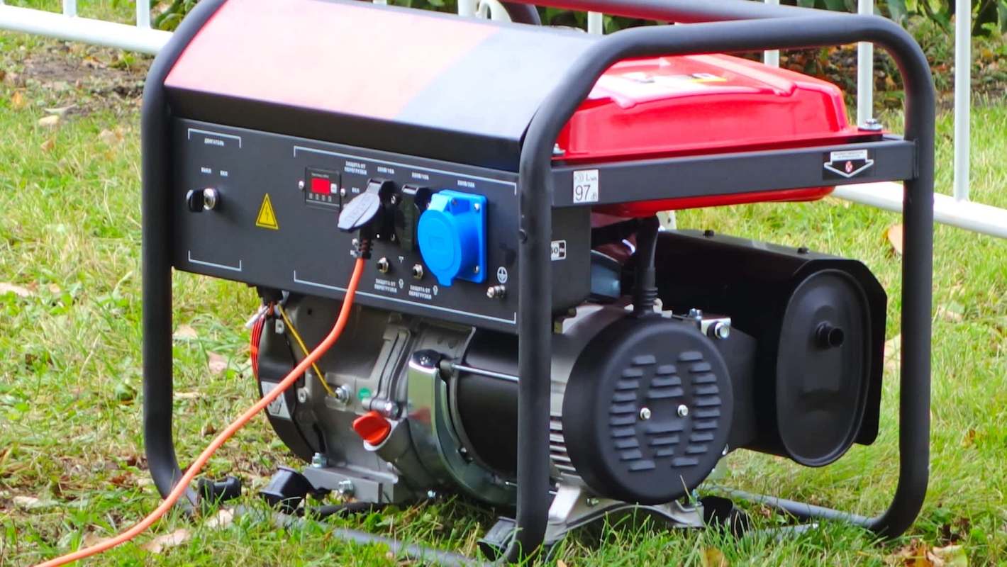 A portable generator on grass with visible electrical connections and control panel.