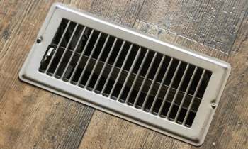 A vent cover installed in a wooden floor.