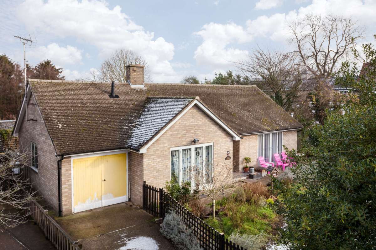 A house with a yellow garage door, two pink chairs on the porch, and a garden with various plants.