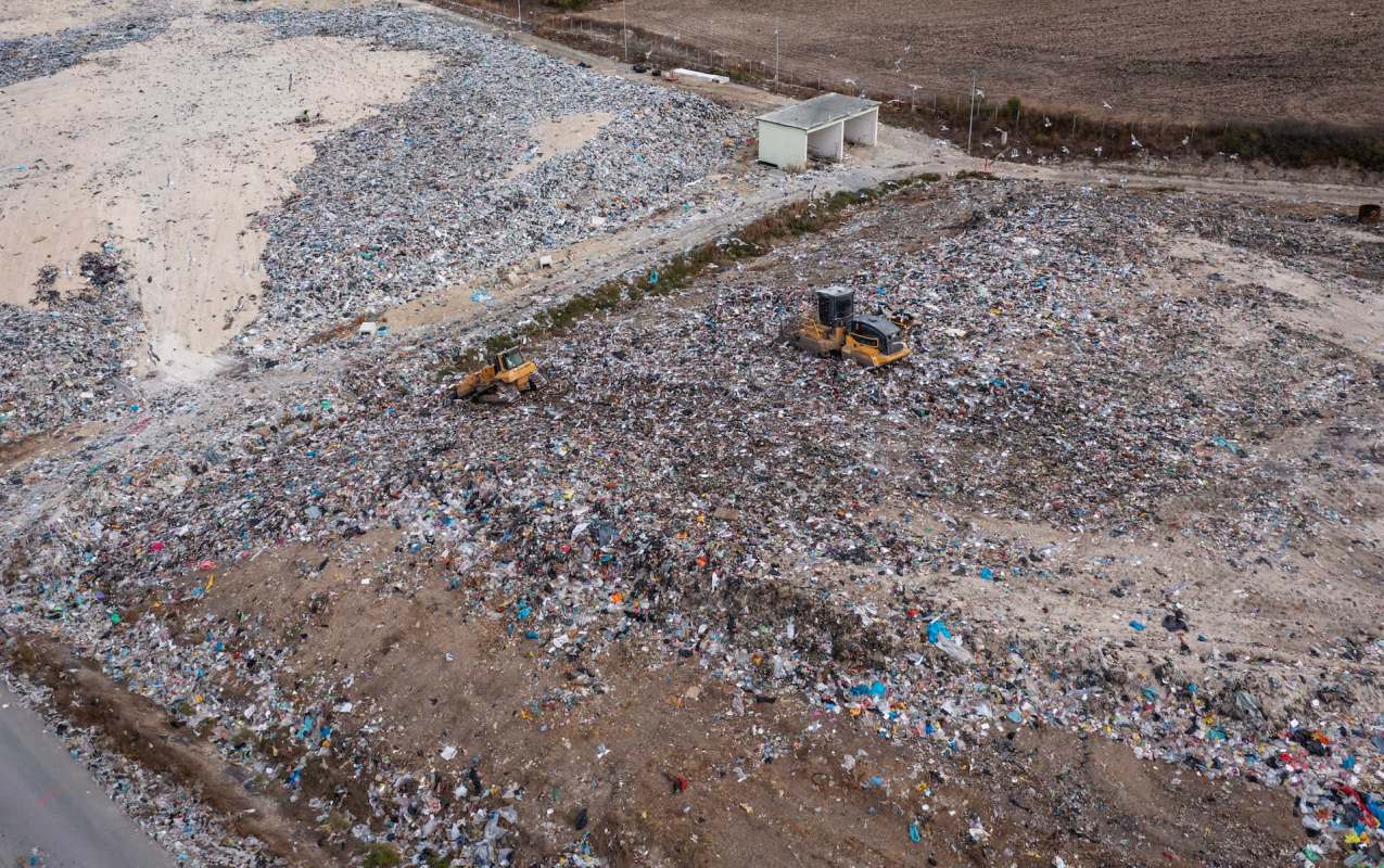 A landfill site with heavy machinery working among piles of waste and debris.