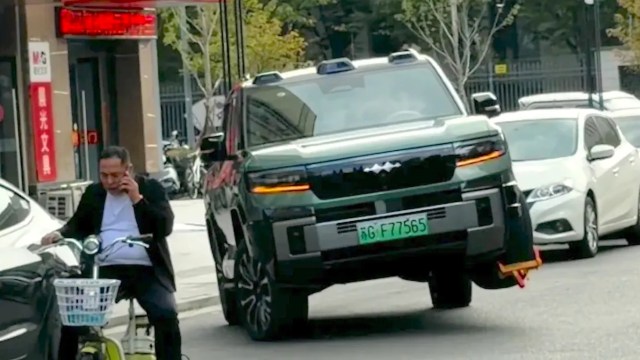 In China, a BYD SUV appears to use its hydraulic suspension to drive off with a parking boot attached