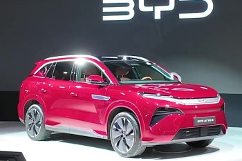A red electric SUV displayed onstage with branding visible in the background.