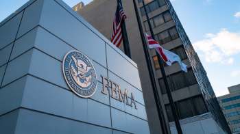 The exterior of a building with the FEMA logo and flags flying nearby.