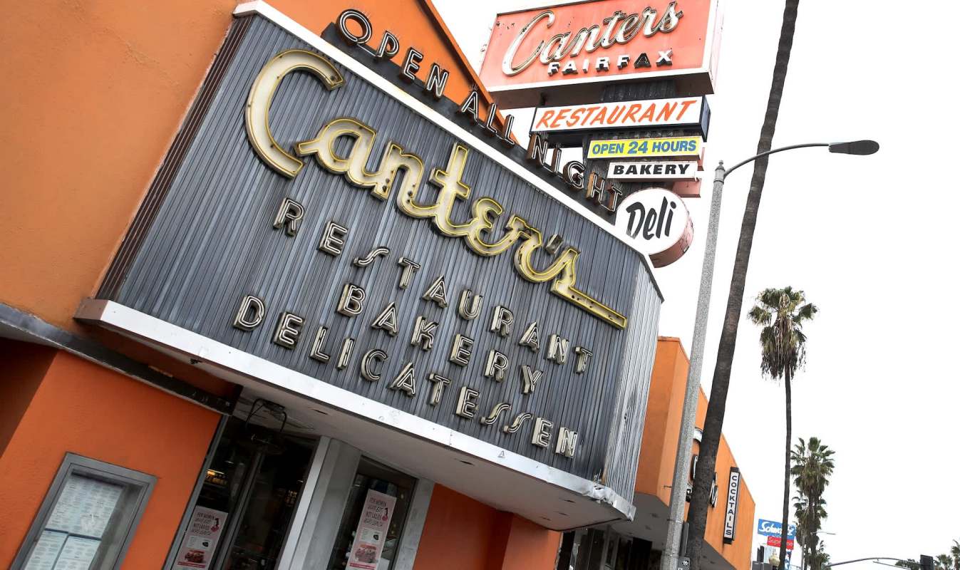 A sign for Canter's Deli in Los Angeles with palm trees nearby.