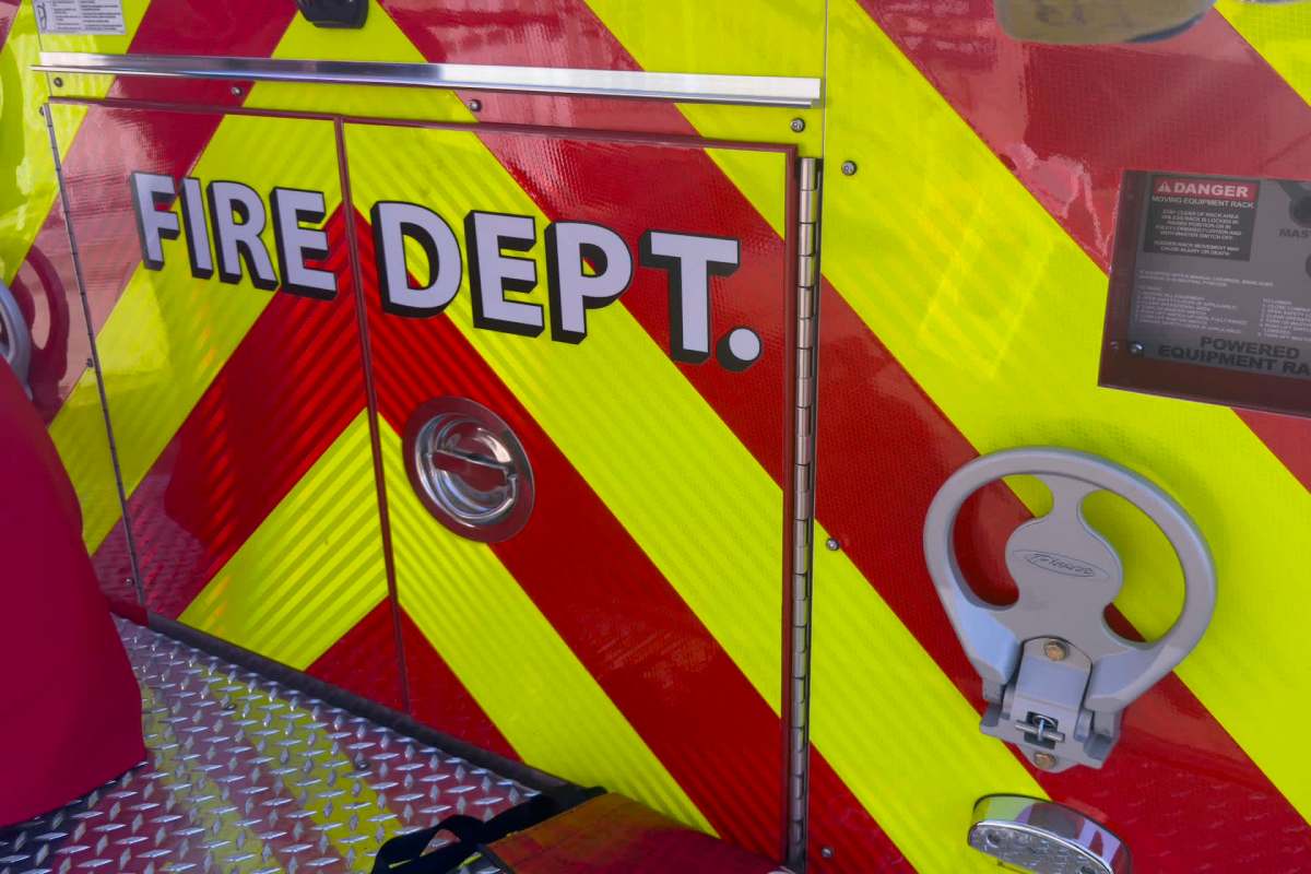 A section of a fire truck with the words "FIRE DEPT." displayed against a red and yellow chevron pattern.