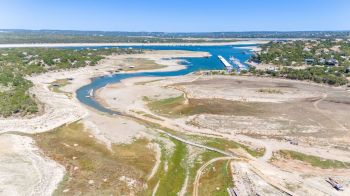 A river flows through a dry landscape with a marina and sparse vegetation.
