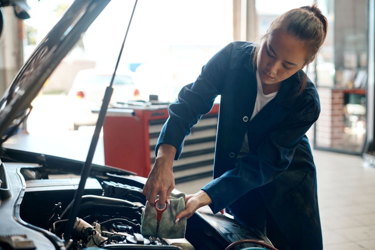A woman measuring a car's oil levels.