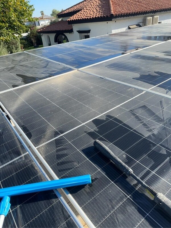 Solar panels on a rooftop with a cleaning tool in the foreground.