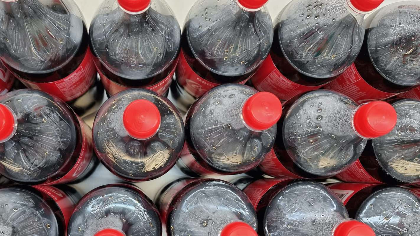 Several plastic bottles of soda with red caps arranged closely together.