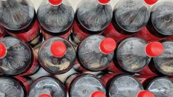Several plastic bottles of soda with red caps arranged closely together.