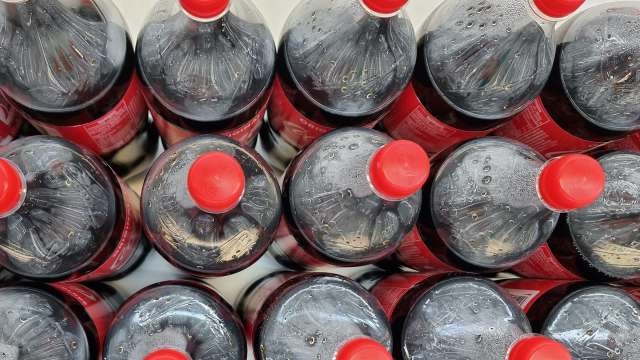 Several plastic bottles of soda with red caps arranged closely together.