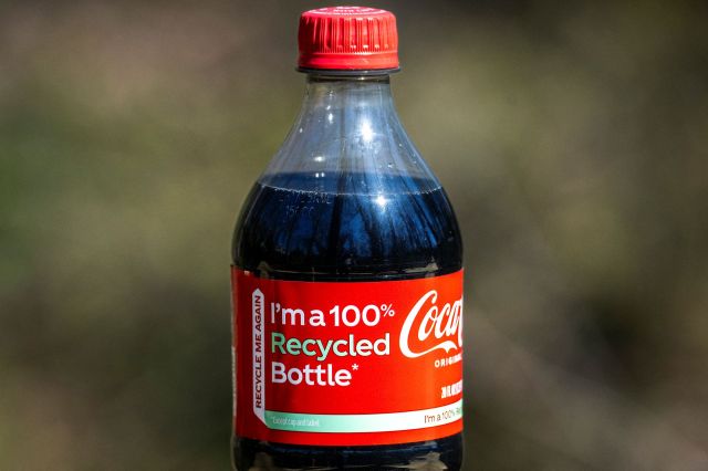 A Coca-Cola bottle with a "100 percent recycled" label.