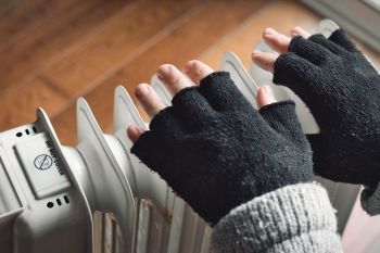 A person holding their hands over a radiator.