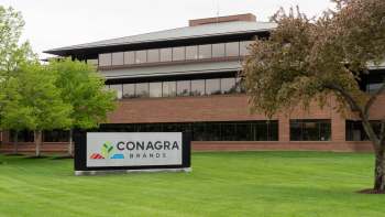 A building with a sign that reads "Conagra Brands" surrounded by green grass and trees.