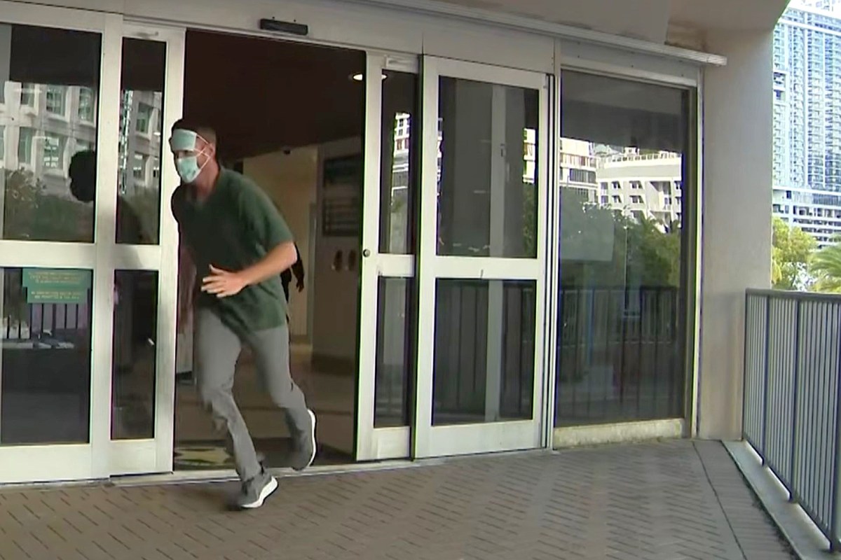A person wearing a mask runs out of a building onto a patio area.