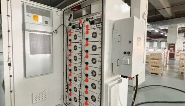 An industrial electrical panel with multiple components and wires in a warehouse setting.