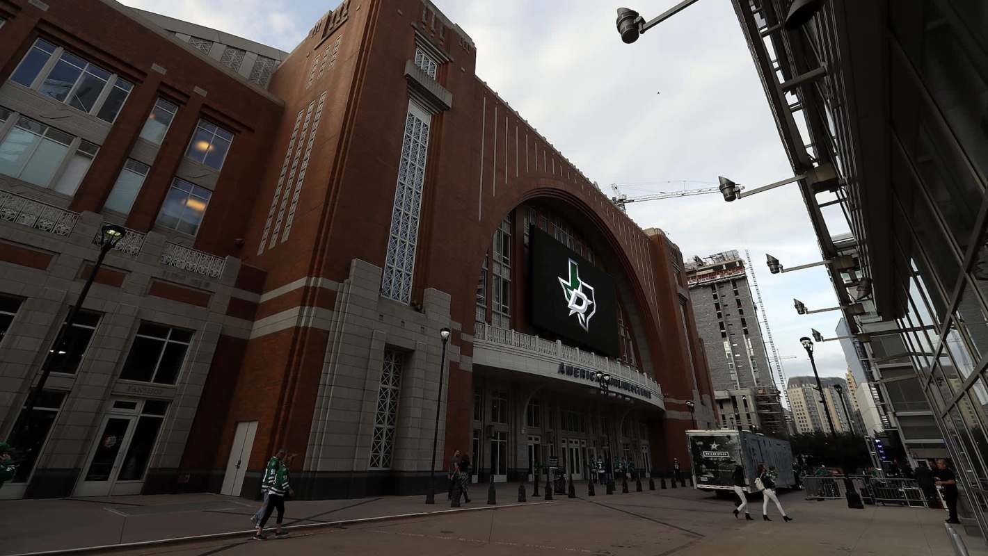 The exterior of an arena featuring a large digital screen with the Dallas Stars logo and a nearby construction site.