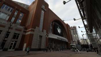 The exterior of an arena featuring a large digital screen with the Dallas Stars logo and a nearby construction site.