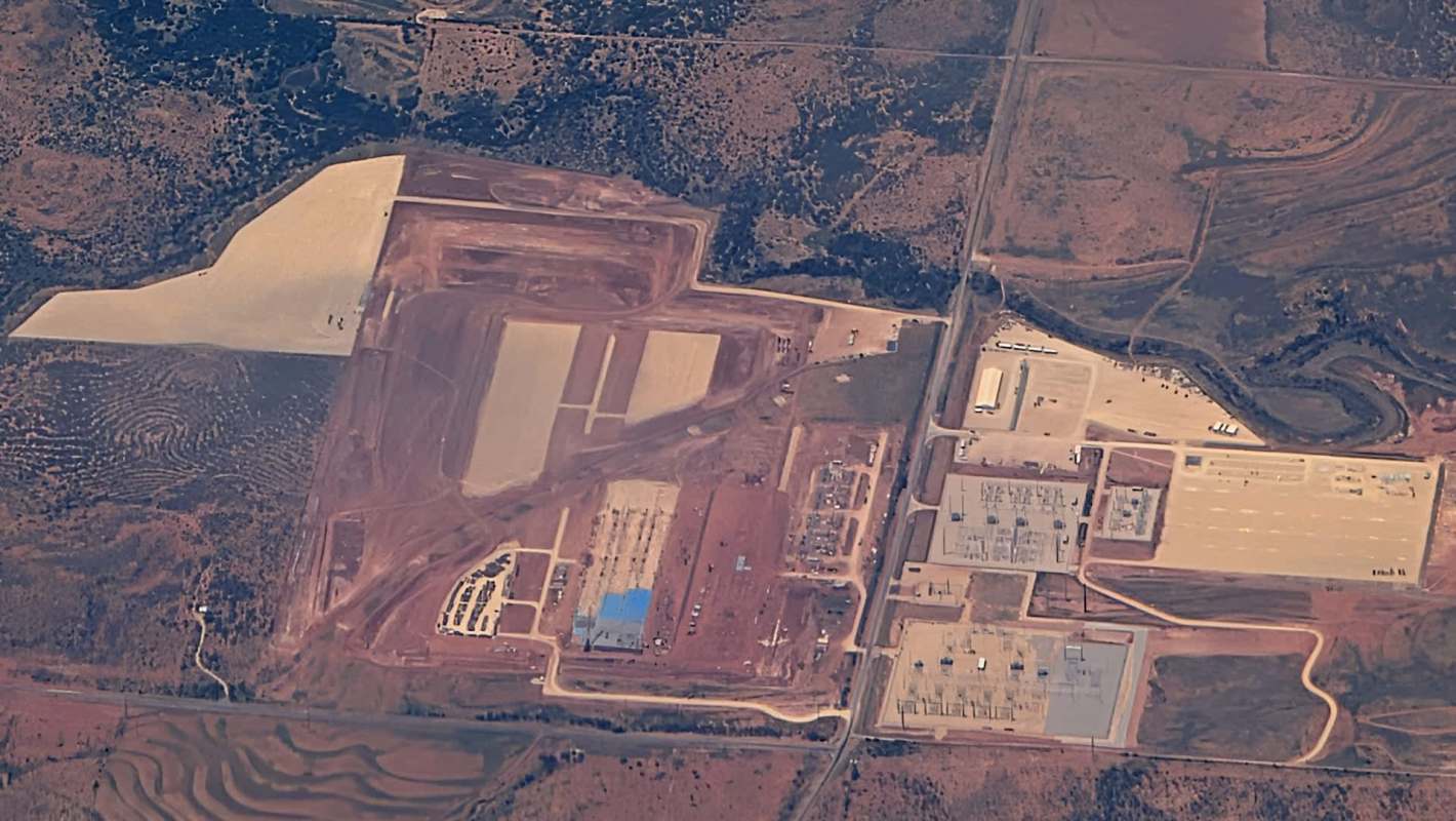 An aerial view of a large construction site with multiple buildings and roadways in a rural area.