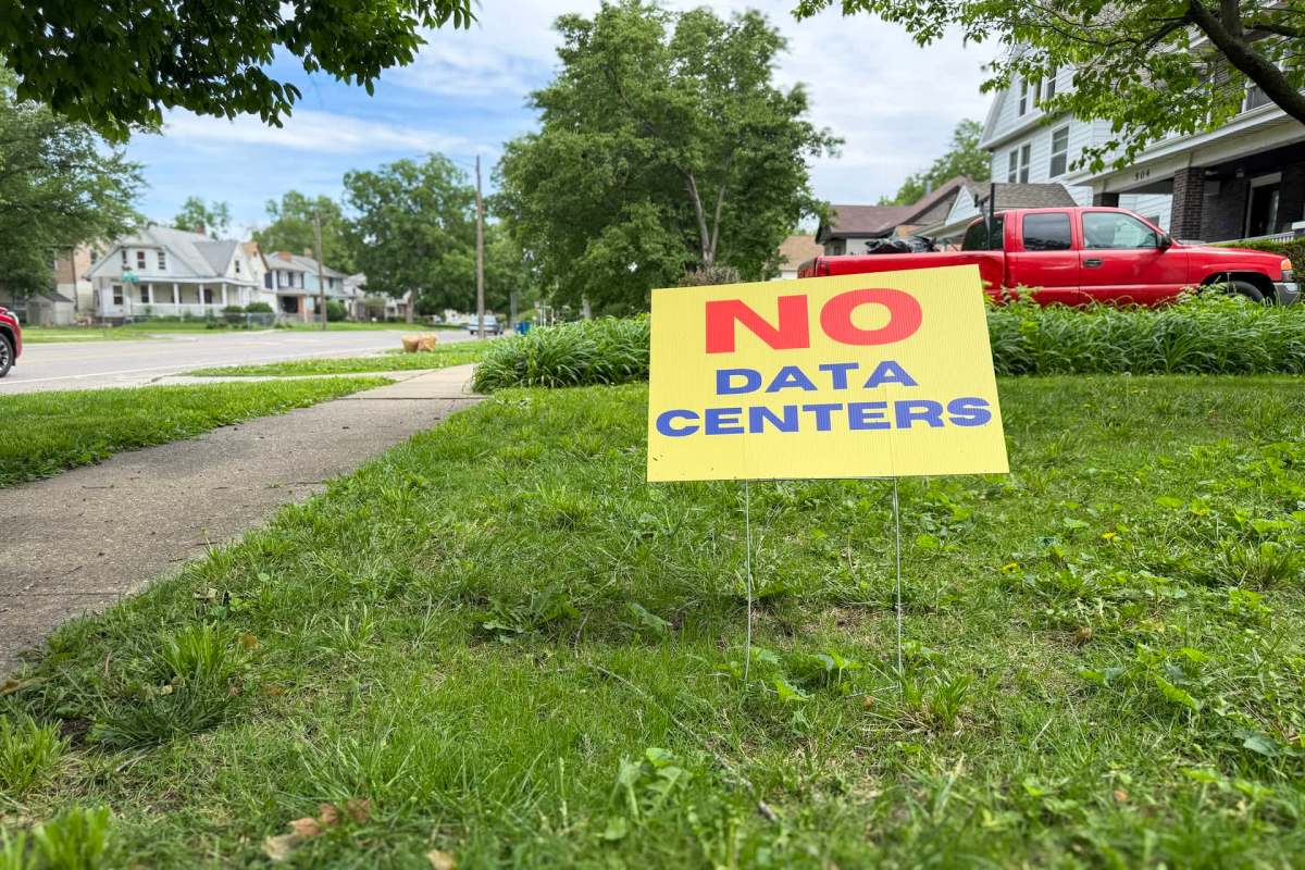 A yard sign reads "NO DATA CENTERS" in bold letters, placed on a grassy area next to a sidewalk.