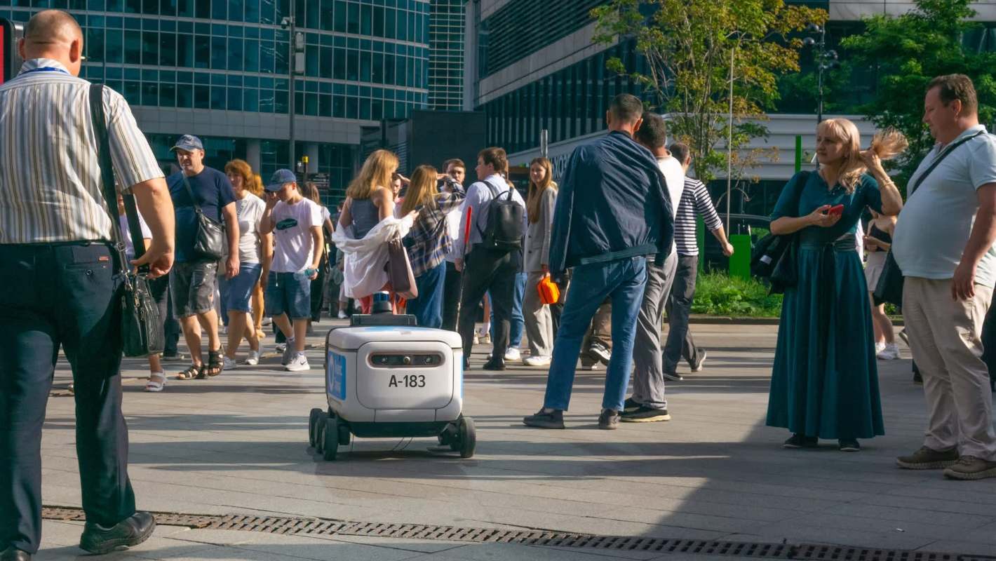 A delivery robot on a crowded sidewalk.