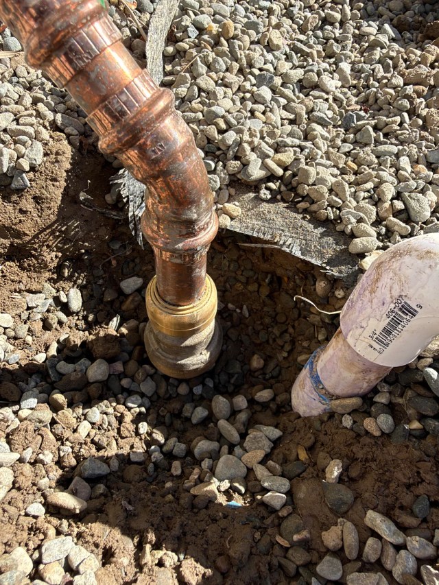 A close-up of two pipes entering the ground.