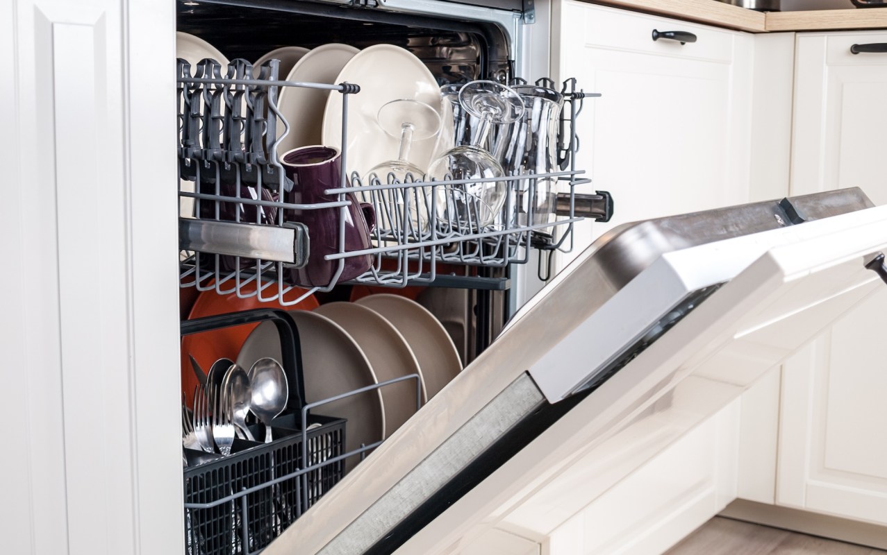 A partially loaded dishwasher with plates, glasses, and utensils inside.