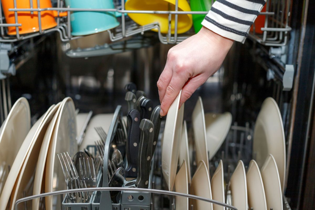 A person unloading a dishwasher.