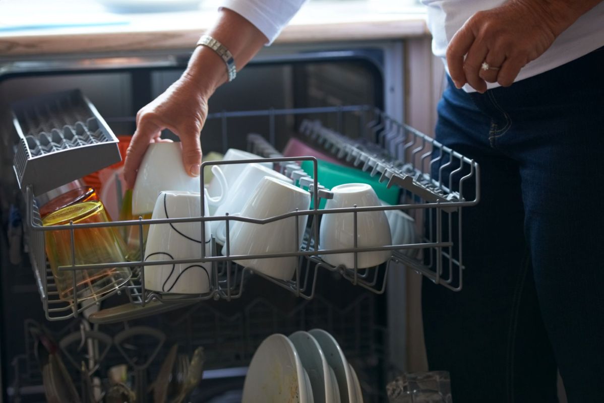 A person loading a dishwasher.