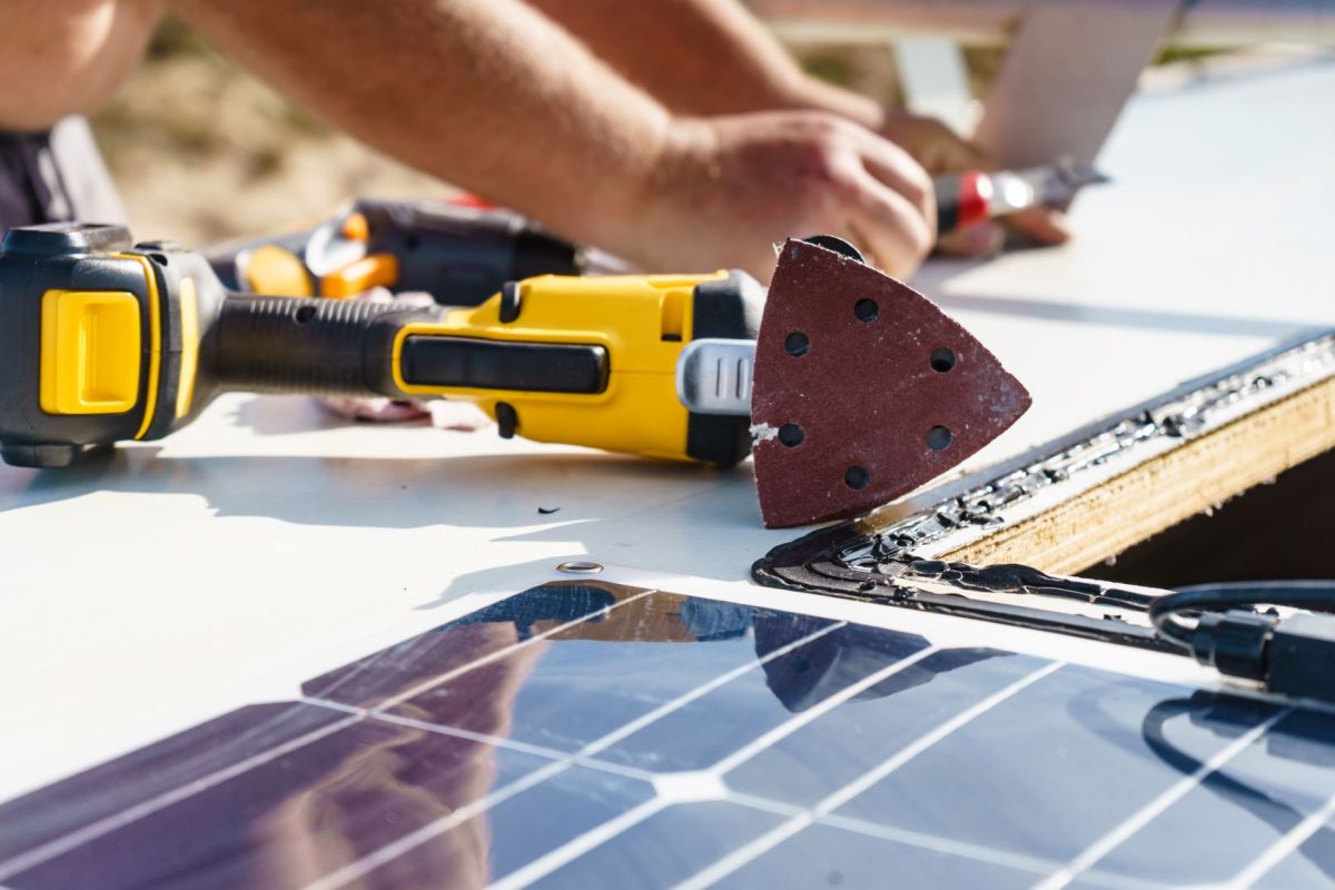 Tools and a solar panel are visible on a work surface, with hands working on modifications.
