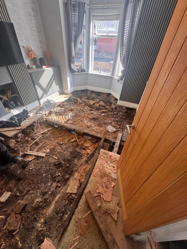 A room under renovation with exposed flooring and a removed section of the floor.