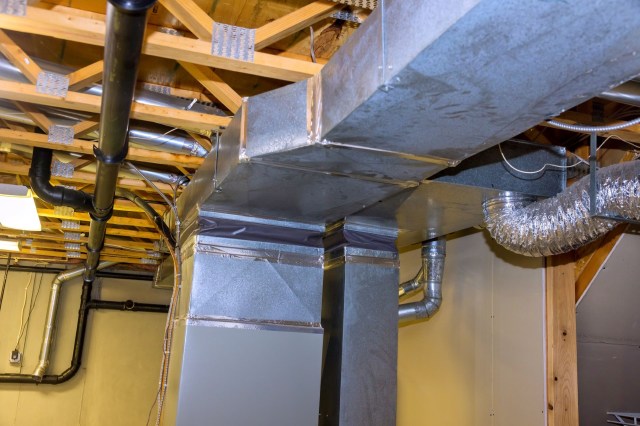 Ductwork and pipes are visible under a wooden ceiling in a basement.