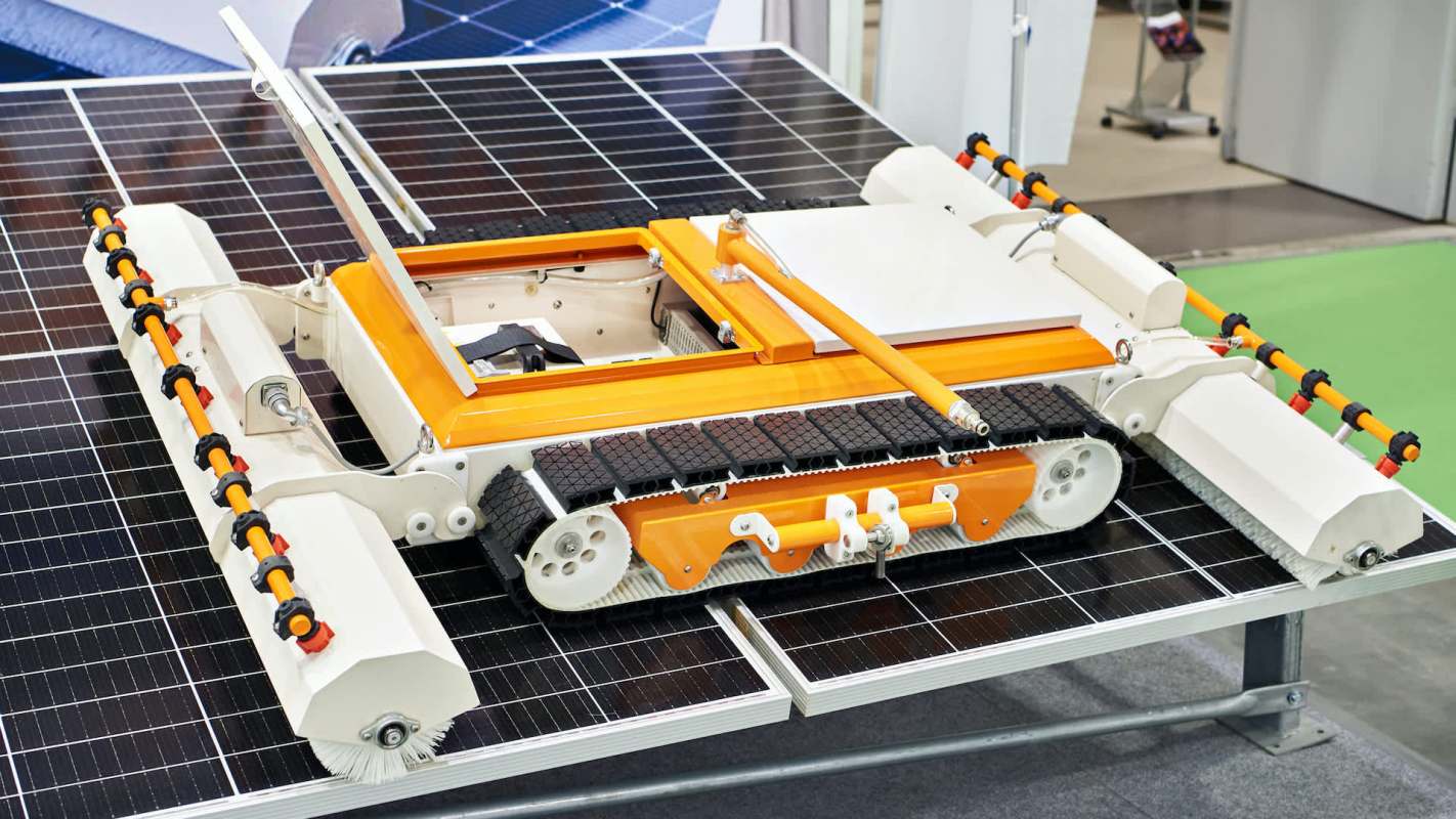 A robotic device designed for cleaning solar panels, positioned on a solar panel surface.