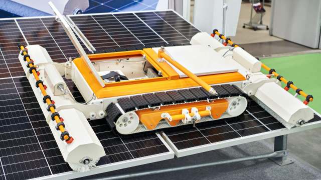 A robotic device designed for cleaning solar panels, positioned on a solar panel surface.