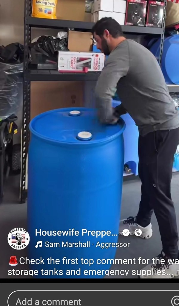 A man standing over a water barrel. 