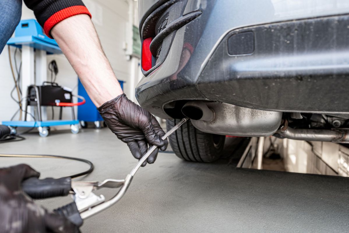 A worker checking a car's exhaust.