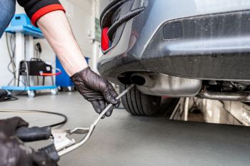 A worker checking a car's exhaust.