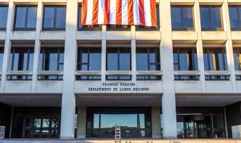 The entrance of the Frances Perkins Department of Labor Building with an American flag displayed above.