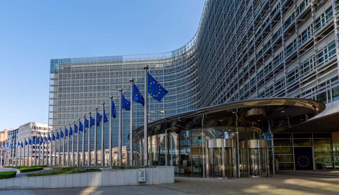 The European Commission building with flags of the European Union in the foreground.