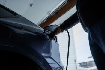 A person charging an EV at home.