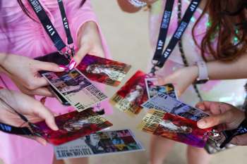 A group of hands holds VIP passes for an event featuring artwork and text related to Taylor Swift.