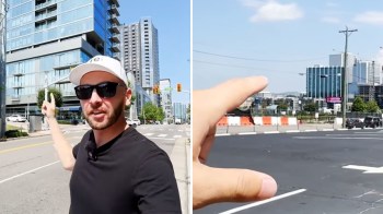 A person points towards a building in an urban setting, with construction and vehicles in the background.