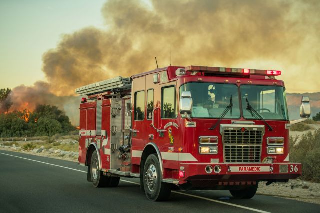 A fire truck near a roadside wildfire.